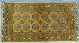 An Afghan rug with central panel of guls and multiple boarders on a mustard ground (198 x 105cm)