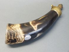 A brass mounted horn powder flask with single suspension loop and vacant silver cartouche to the