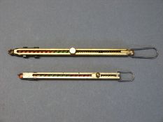 Two brass percussion cap dispensers, each with a single suspension loop,