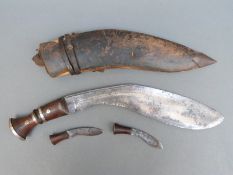 A kukri in leather-covered sheath with two smaller knives attached,