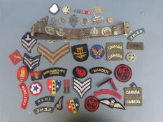 A leather belt of military cap badges to include Argyll & Sutherland, Royal Canadian Engineers,