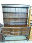 An early 20thC oak dresser with plate rack top having pie crust edge,
