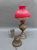 A brass oil lamp with red glass shade,