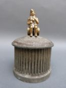 An 18th / 19thC cast figural tobacco jar topped with brass figure seated on a barrel,