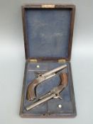 A pair of percussion hammer action side by side pistols with chequered locks, carved reeded grip,