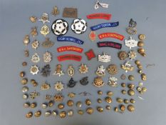 A quantity of military cap badges, buttons and insignia to include Gloucestershire Regiment,