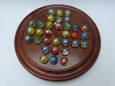 A large solitaire set with turned wooden board and iridescent marbles