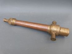 A vintage copper and brass fire hose nozzle with adjustable side valves,