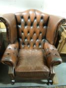 A brown Chesterfield wing-back chair with footstool