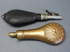 A copper and brass powder flask with embossed decoration of a dog's head surrounded by scrolling