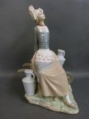 A Lladro figurine of a milkmaid seated on a barrow with milk churns