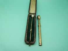 A gold pencil with chased foliate design and hardstone top together with with a stick pin