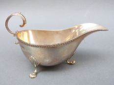 An Edward VII hallmarked silver sauce boat raised on three feet with scroll handle, Chester 1909,