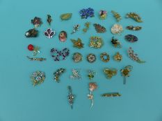 A collection of flower and foliate design brooches to include ceramic crown china,