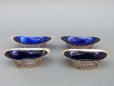 Four Victorian and later hallmarked silver basket shaped open salts with blue glass liners,