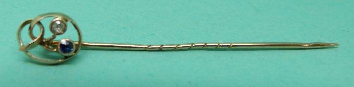 A 15ct gold stick pin set with a sapphire and a diamond