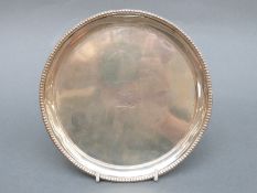 A Victorian hallmarked silver circular card tray with beaded edge raised on three ball and claw