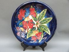 A Moorcroft charger in Hibiscus pattern on a blue ground, 36.