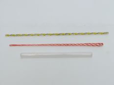 Three glass canes two with multicoloured decoration the other of hollow form,