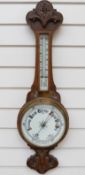 An early 20thC aneroid wall barometer and thermometer combination, in carved oak case,