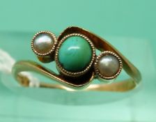 A 9ct gold ring set with a turquoise cabochon and two seed pearls (size L)