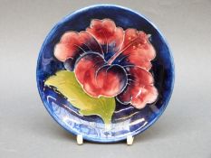 A Moorcroft pin dish in Hibiscus pattern on a blue ground, 11.