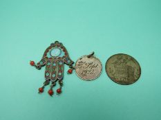 A white metal Nepalese/ Tibetan pendant in the form of the hand of Fatima set with enamel and coral