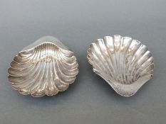 A pair of hallmarked silver shell shaped dishes raised on three ball feet,