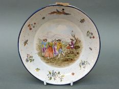 A 19thC tin glazed dish with hand decorated scene of dancers and musician in rural setting