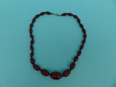 A cherry amber necklace of graduated oval beads,