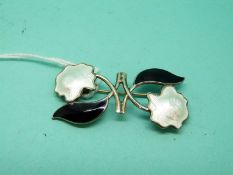 A silver brooch set with black and white enamel in a foliate design
