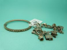 A silver charm bracelet and a bangle set with seed pearls