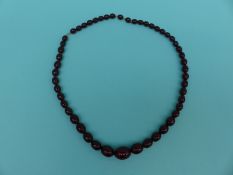 A cherry amber necklace of graduated oval beads,