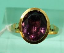 A yellow metal ring set with an oval amethyst in a foiled setting (Size N)