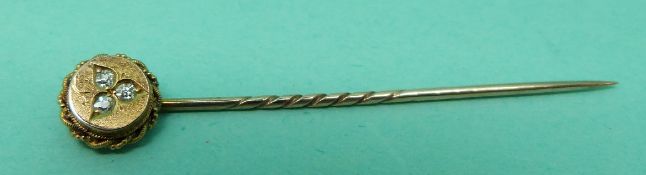 A 15ct gold stick pin set with three diamonds