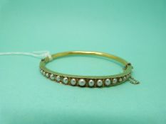An Edwardian 15ct gold bangle set with graduated seed pearls
