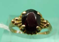 A 9ct gold ring set with an oval cut garnet (size M)