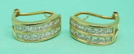 A pair of 18ct gold earrings each set with fourteen princess cut diamonds in two rows,