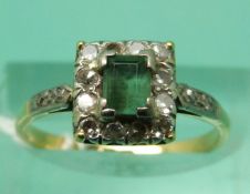 An 18ct gold ring set with an emerald-cut emerald surrounded by diamonds in a platinum setting
