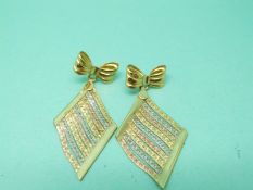 A pair of tricolour gold earrings with bow studs and drop diamond section