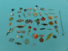 A collection of various brooches to include thistle, dolphin, angel, flowers, articulated clown,