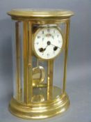 A brass cased mantel clock with four bevelled and curved glass panels,