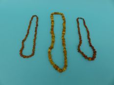 Three amber necklaces of various colours,