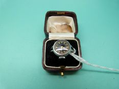 A ring set with a small watch with black face