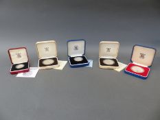 Five cased commemorative coins comprising a silver £2 Commonwealth example of 1986,