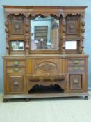 An oak carved sideboard, the top with triple bevelled edge mirrors and carved bulbous supports,
