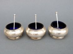 A set of three George V hallmarked silver open salts with blue glass liners, Sheffield 1918,
