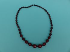 A cherry amber necklace of graduated oval beads,