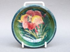 A Moorcroft pedestal dish in Freesia pattern on a green ground,