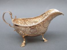 A Victorian hallmarked silver sauce or gravy boat with scroll handle raised on three feet,